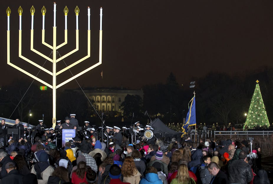 People gather for the lighting of the National Hanukkah Menorah, with the White House in the background and the Christmas Tree on the right, in Washington D.C.