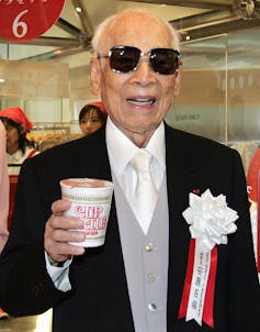 Man in sunglasses and suit poses with food package.