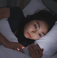 A teen in bed with a smartphone