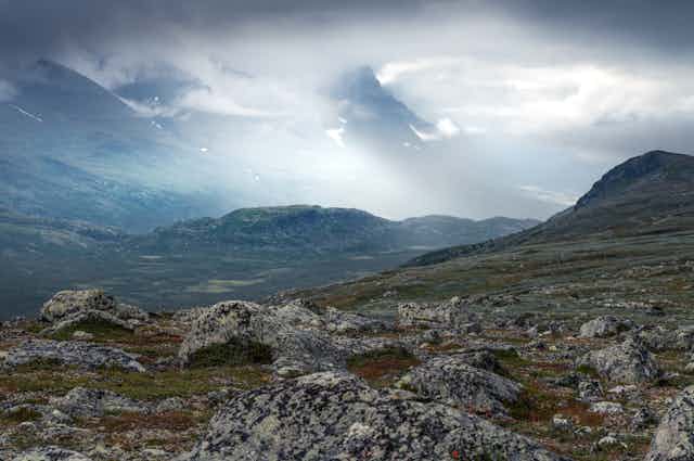 Rocky, mountainous landscape with swirling clouds in the background.