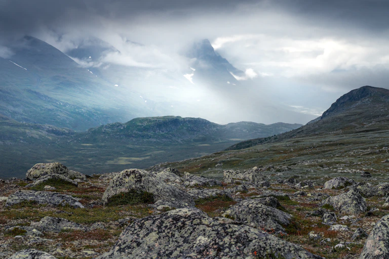 Rocky, mountainous landscape with swirling clouds in the background.