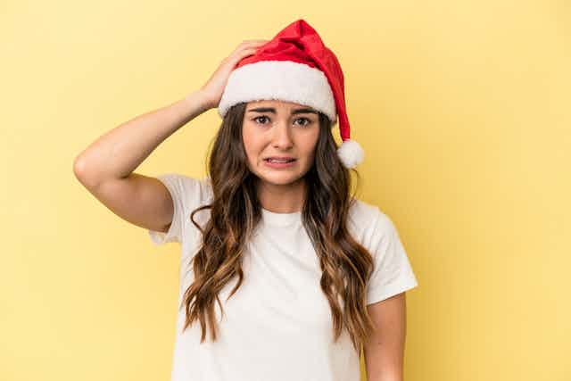 Young woman wearing Santa hat looking confused
