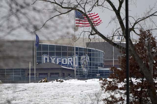 Oxford High School is seen in the snow, with an American flag fluttering in front of it.