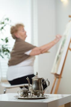Older woman painting at home.