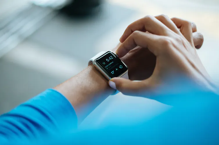 Hands with white nail polish adjust a digital watch.
