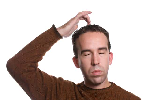 Man with eyes closed tapping the top of his head