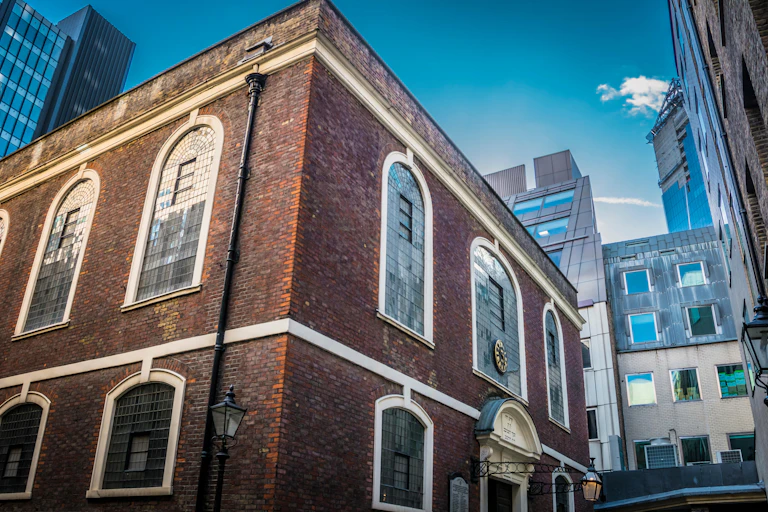 The red-brick synagogue nestles between townhouses and tall city towers.