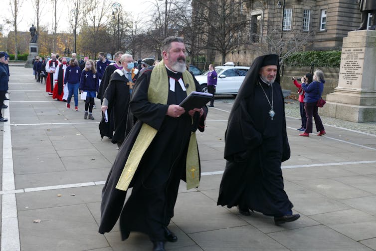 People in religious dress process down a street