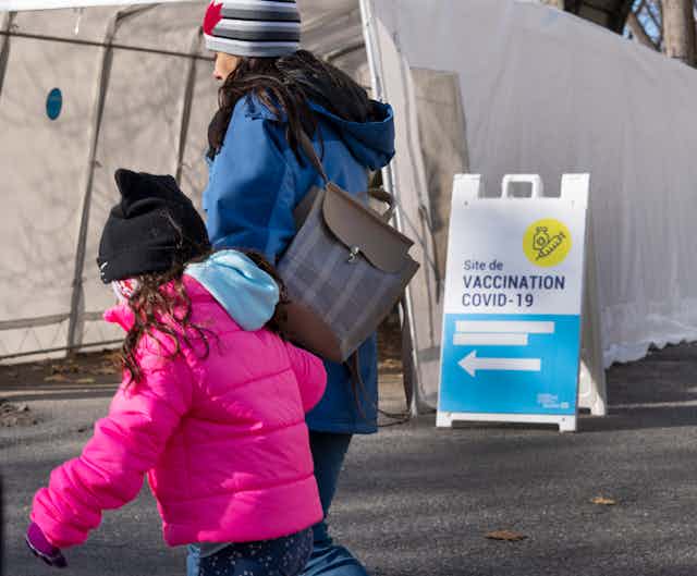 Une femme et un enfant passent devant une clinique de vaccination COVID-19