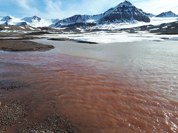 Brown water meets blue water, icy mountains in background