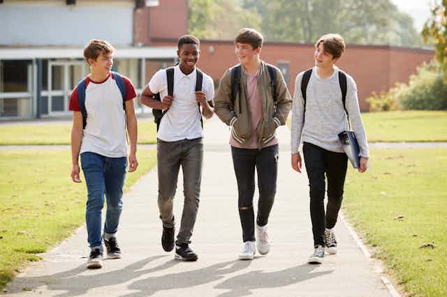 Four teenage boys walking outside at school