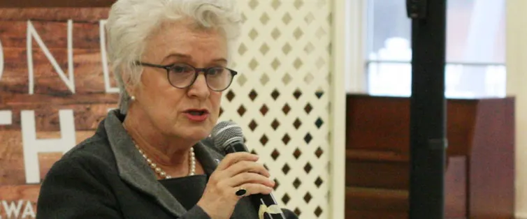 A woman holding the microphone as she delivers an address to an audience.