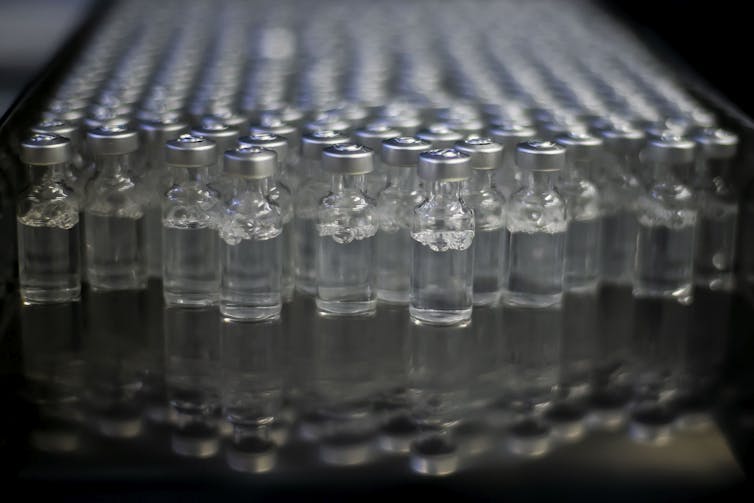 Dozens of vaccine vials on a table.