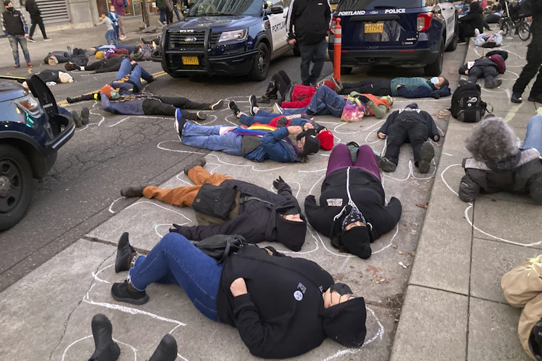 protestors lie in the street with chalk body outlines around them