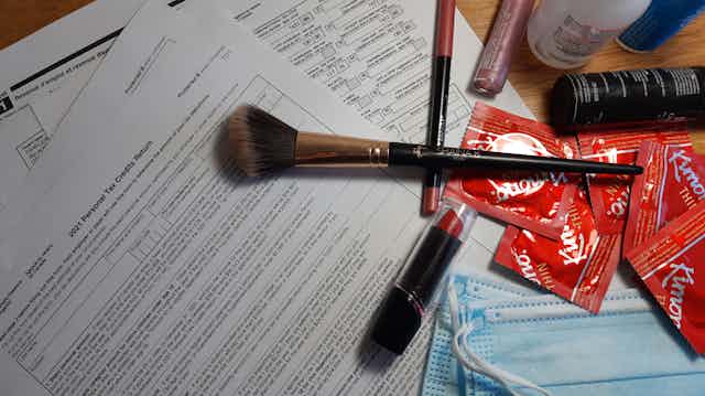 A personal tax credit return form is shown with disposable masks, makeup and condoms layered on top