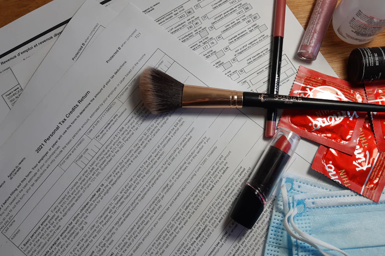 A personal tax credit return form is shown with disposable masks, makeup and condoms layered on top