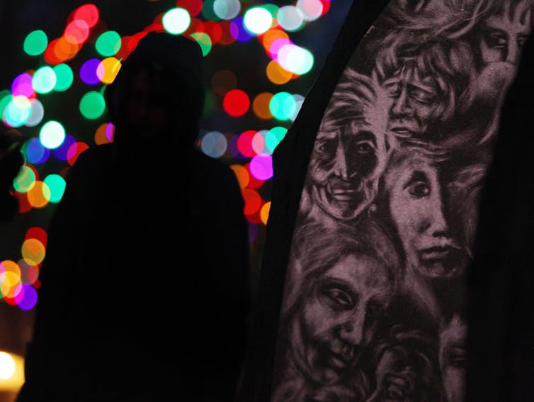 a silhouette of a woman in seen beside a monument with christmas lights in the background