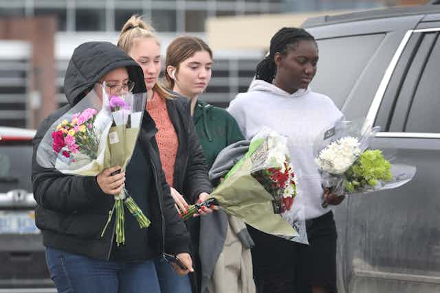 A group of girls carry flowers in their hands.