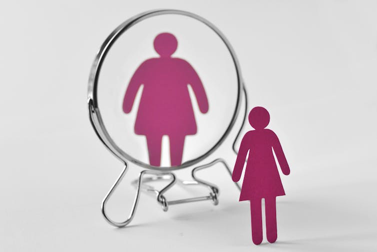 Illustration of a normal sized female figure reflected as much larger in a mirror