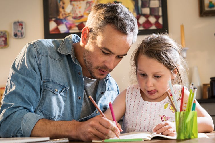 Father helps his daughter with homework.