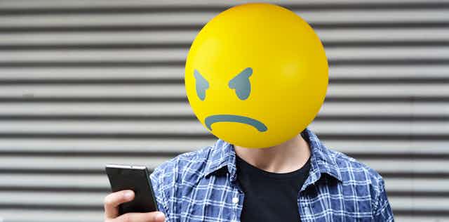 Photoillustration of man with angry emoji head.