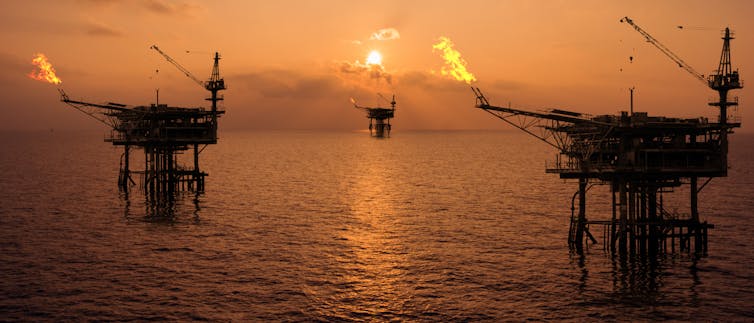 gas flares from offshore rigs at sunset