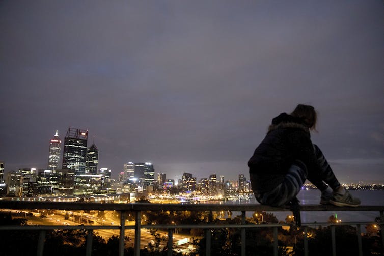 silhouette of person sitting in front of city skyline