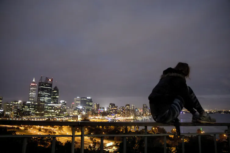 silhouette of person sitting in front of city skyline