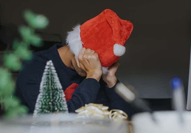 Man wearing Santa hat with head in hands