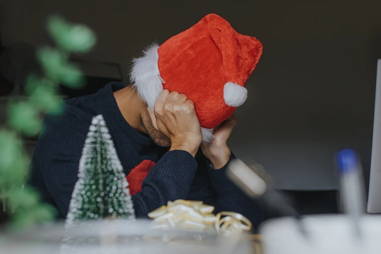 Man wearing Santa hat with head in hands