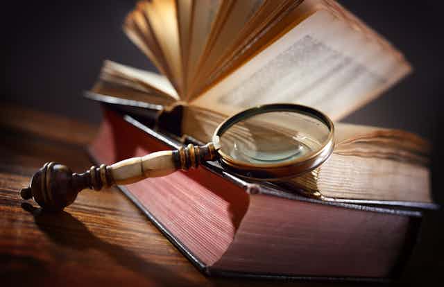 Close-up of an old magnifying glass resting against a stack of old books