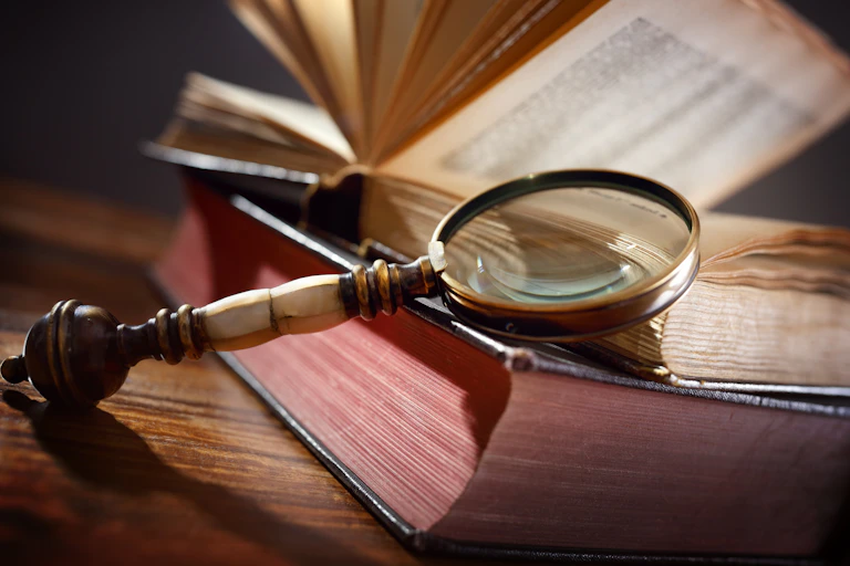Close-up of an old magnifying glass resting against a stack of old books