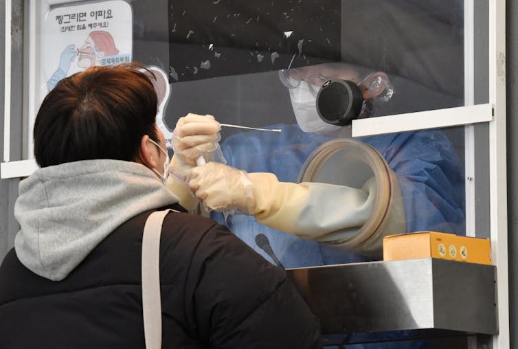 Prélèvement nasal sous haute sécurité à l’aéroport de Séoul