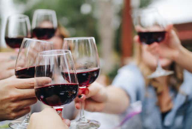 People clinking glasses of red wine