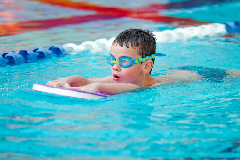 A boy learns to swim in a pool.