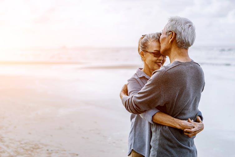 older couple hugging on a beach.