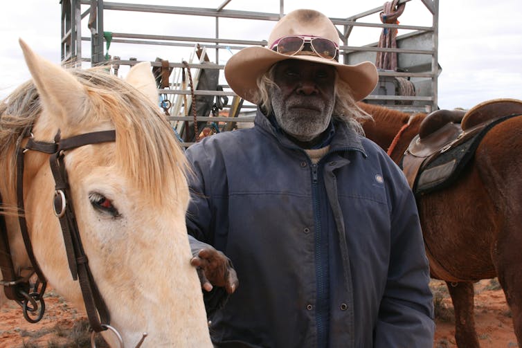 An Aboriginal stockman poses with his horse.