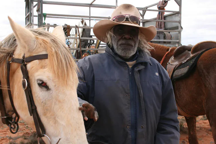 An Aboriginal stockman poses with his horse.