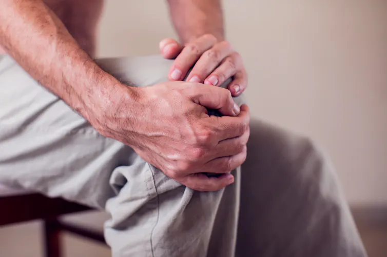 man holds sore knee