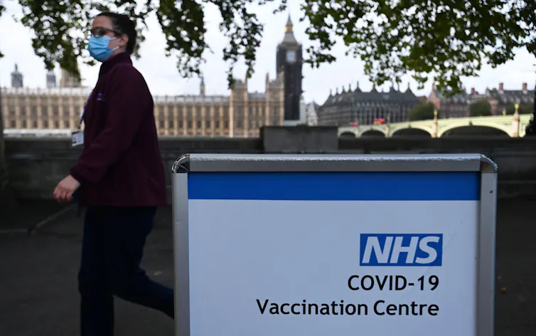 A person walking past a sign for a COVID vaccination centre