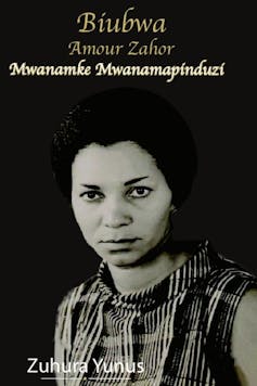 An image of a woman in black and white against a dark backdrop; she looks straight into camera with a wry expression.