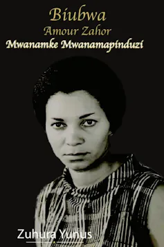 An image of a woman in black and white against a dark backdrop; she looks straight into camera with a wry expression.