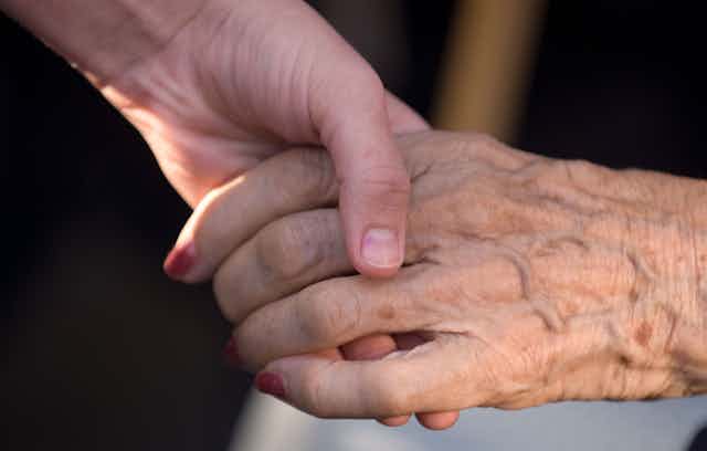 A younger person holding an older person's hand