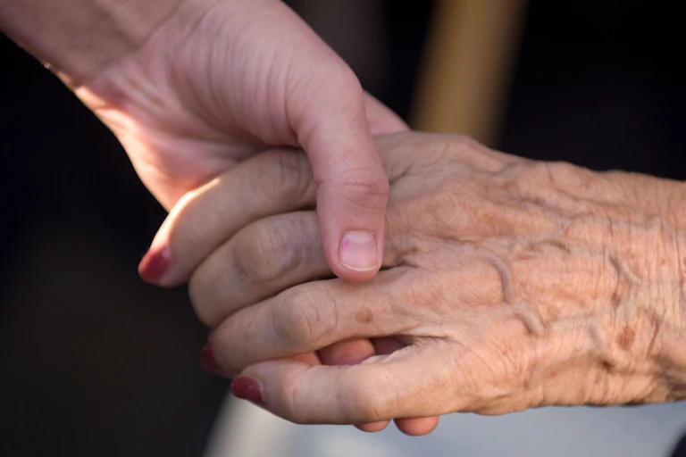 A younger person holding an older person's hand