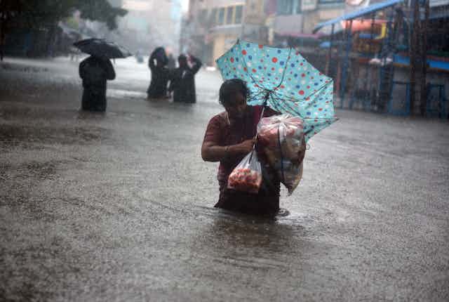 A woman up to her waist in water in a flooded street in Chennai during a downpour.