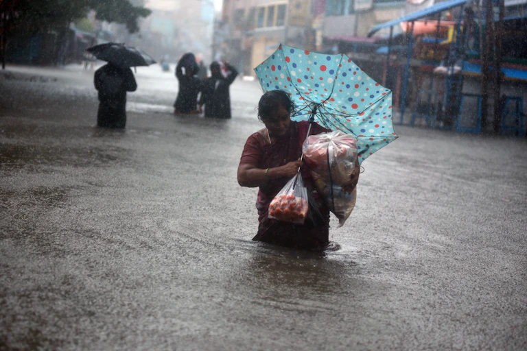 A woman up to her waist in water in a flooded street in Chennai during a downpour.