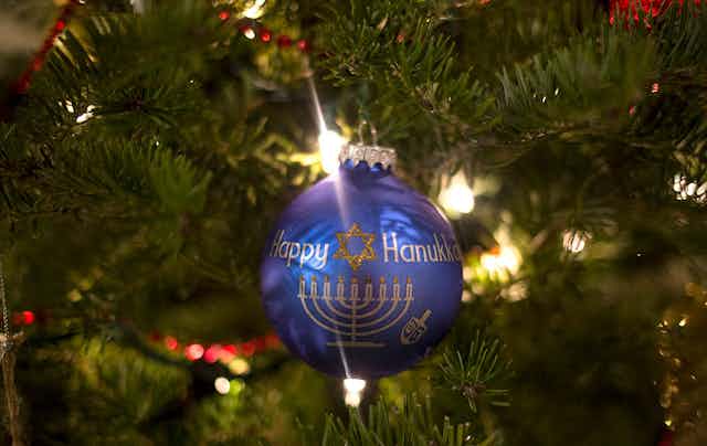 An ornament on a Christmas tree reads, "Happy Hanukkah."
