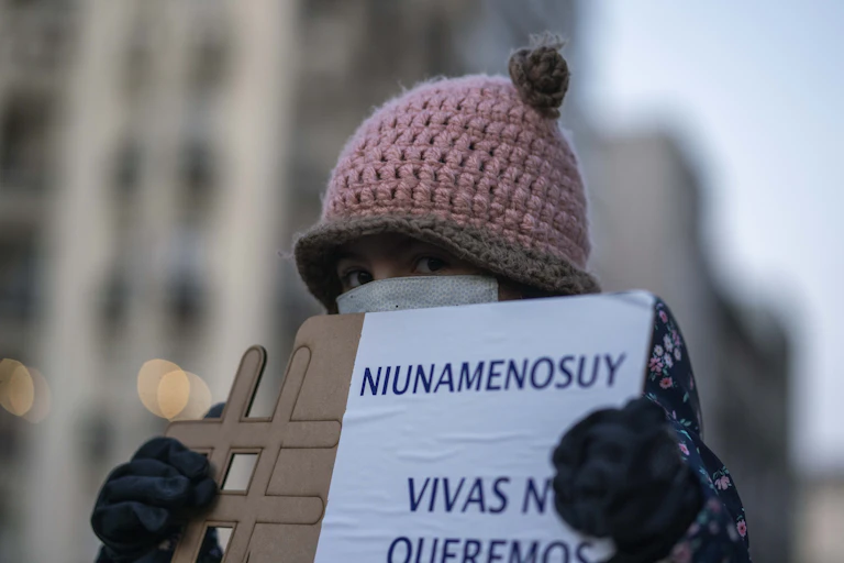 A girl wearing a face mask to prevent the spread of new coronavirus holds a sign that reads in Spanish "Not one less