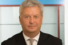 A man with grey hair smiles.