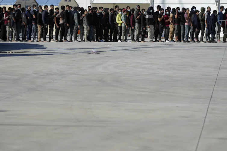 Hundreds of people stand in a long line.